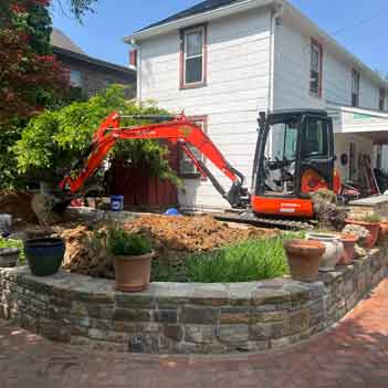 Excavating Contractor - Photo of an excavator leveling a retaining wall garden.  